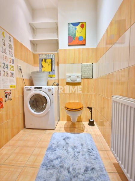 A bathroom with a washing machine, toilet, and an art painting in a 3-room apartment.