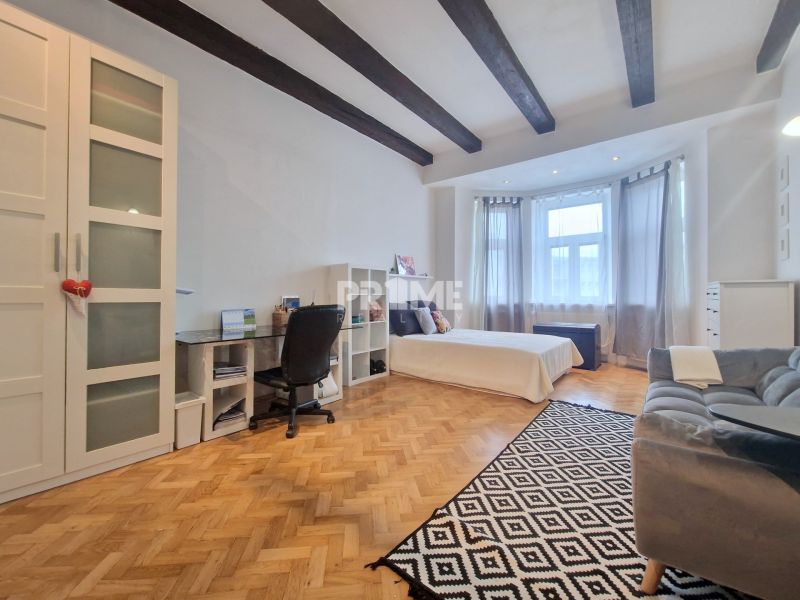 A bedroom in a 3-room apartment with a wooden decor floor and ceiling beams.
