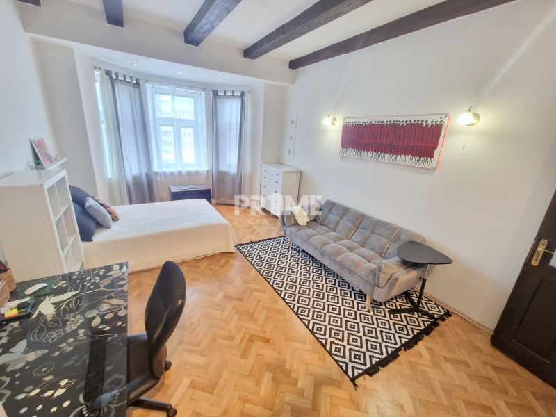 Partially furnished 3-room apartment with a sofa, table, and wooden decor flooring.