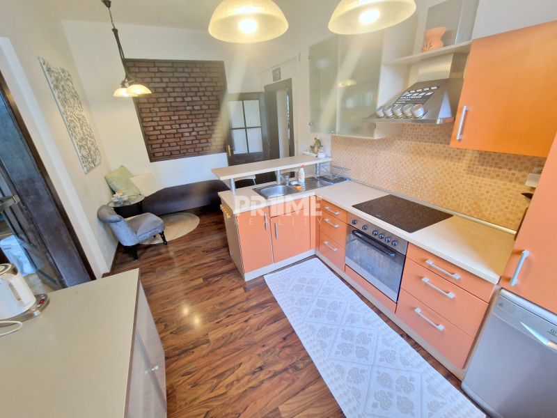 A kitchen with an orange cabinet, a sofa, and a wooden decor floor in a 3-room apartment.