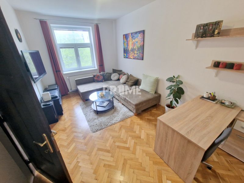 A room in a 3-room apartment with a sofa, television, and a floor with a wooden decor.