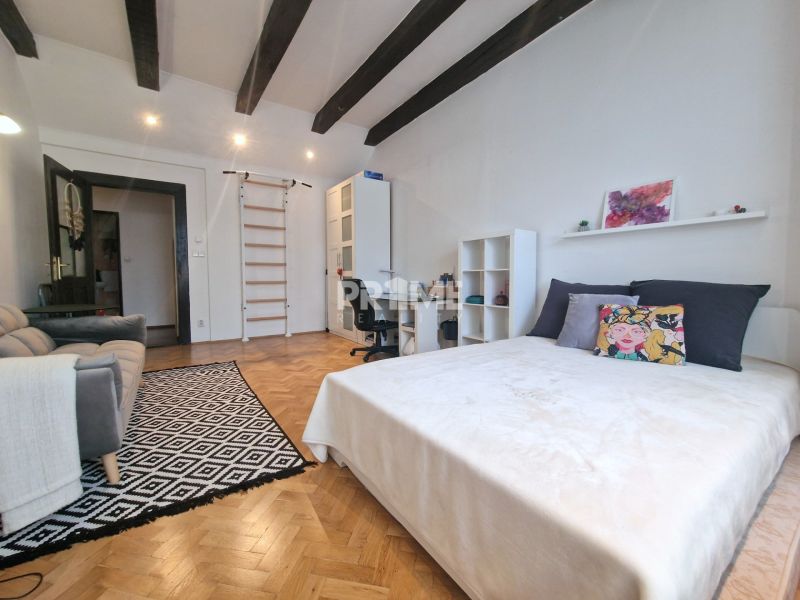 A room with a bed, a sofa, and a floor with a wooden decor in a three-room apartment.