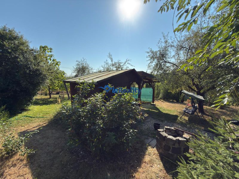Cottage on the Vineyard in Lučenec surrounded by greenery and trees, with a fire pit in the garden.