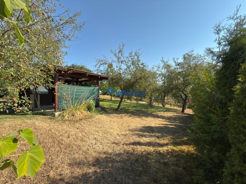 A garden with a cottage surrounded by trees on Vinica Street in Lučenec.