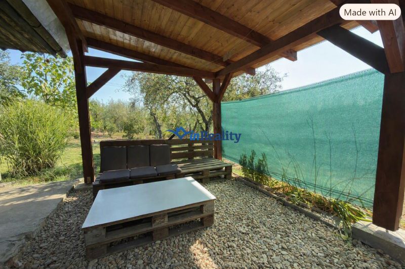 A wooden pergola with seating at a cottage in Vinica in Lučenec surrounded by greenery.