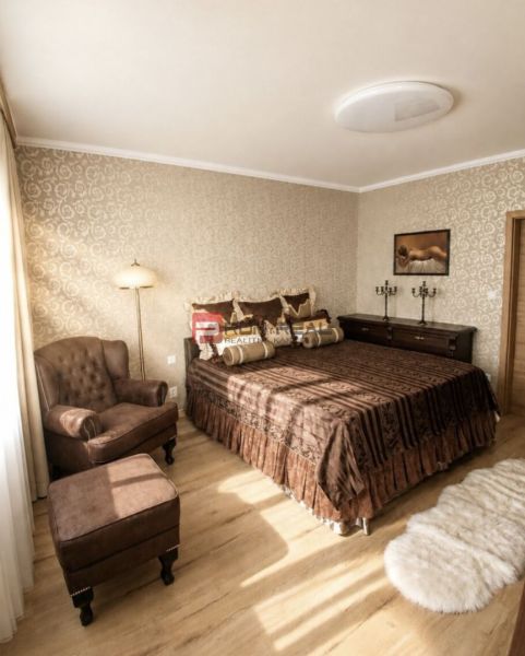 A bedroom with a chair and a bed, a wooden decor floor, warm tones.