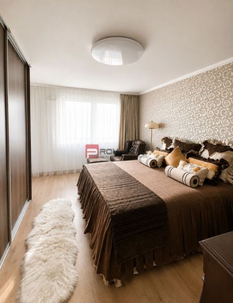 Bedroom in a 2-room apartment with wood-patterned flooring, a cozy bed, and patterned wallpaper.
