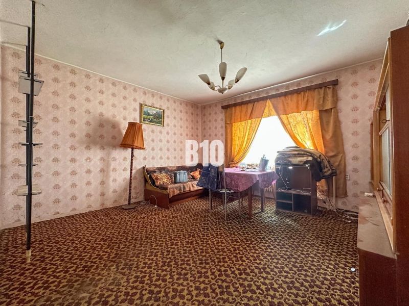 A room with a patterned carpet, a sofa set, and a table with a tablecloth.
