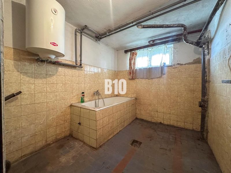 Bathroom in a family house with tiles and a bathtub, with a lower window and a gas boiler.