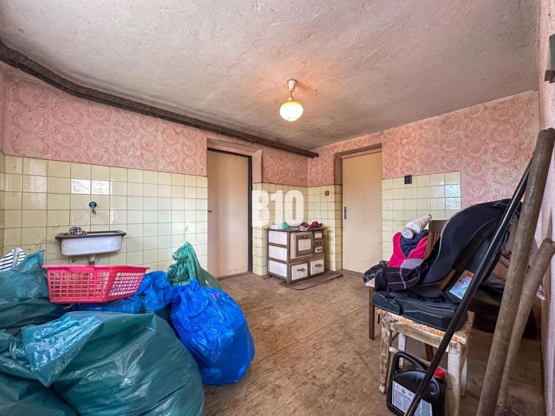Interior of a family house with a sink, wood-patterned flooring, and stored items.