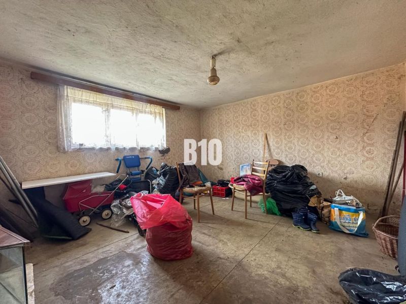 Room in a family house with wallpaper, lots of things, and a baby stroller.