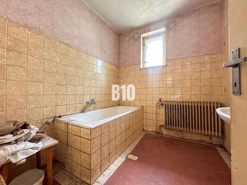 Bathroom in a family house with a bathtub and ceramic tiles on the walls.