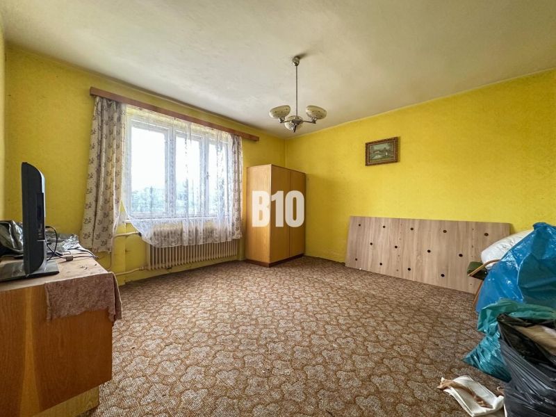 A room in a family house with a carpet, furniture, and curtains on the window.