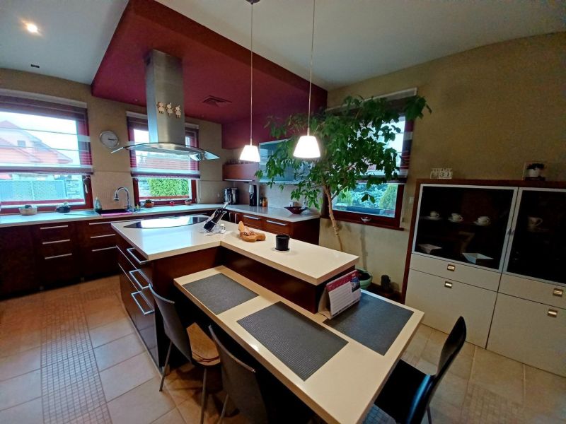 A kitchen in a family house with an island, a dining table, and large windows for light.