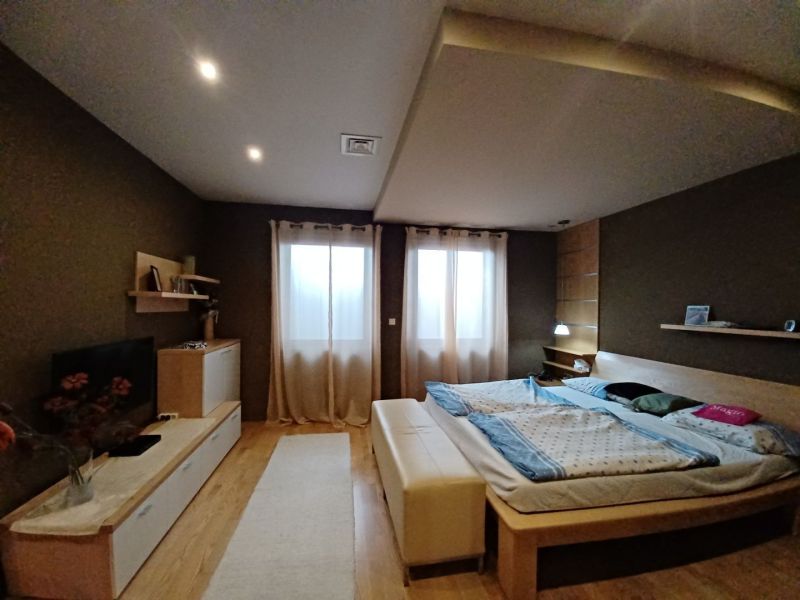 Bedroom with a bed, wooden decor flooring, and comfortable furnishings in a family house.