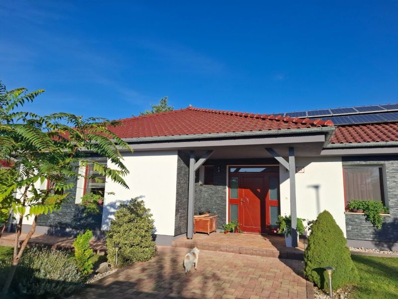 A family house in Nové Zámky with a red roof, solar panels, and a garden.