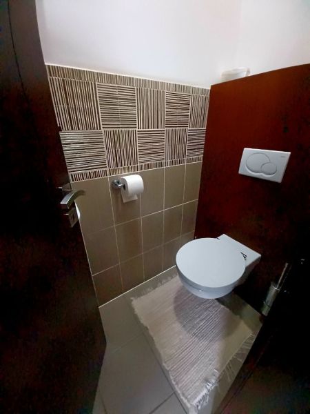 A bathroom in a family house with ceramic tiles and a wall-mounted toilet.
