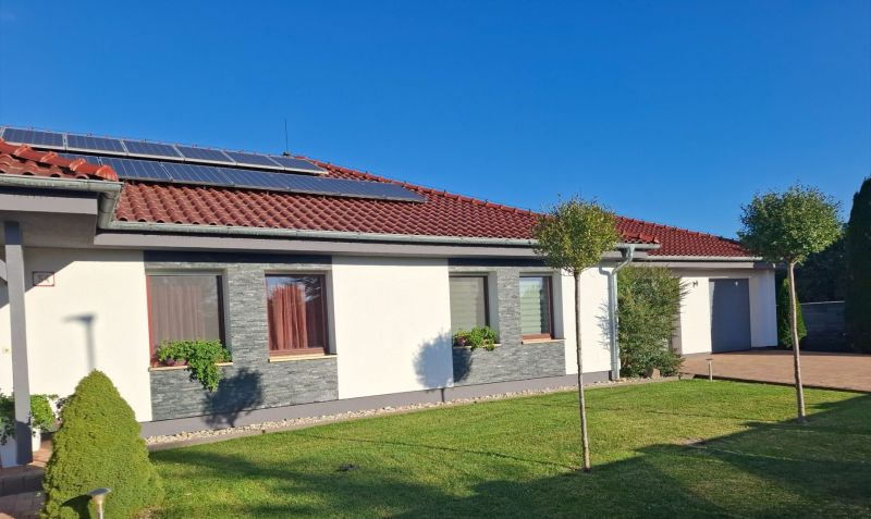A family house in Nové Zámky with solar panels on the roof and a landscaped garden.