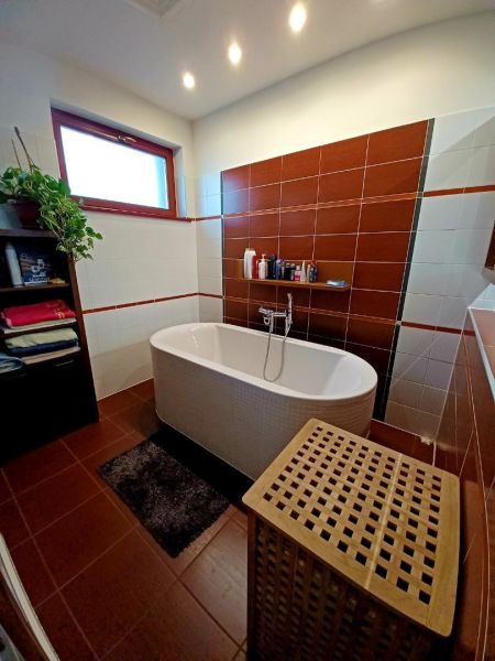 Bathroom in a family house with a bathtub, shelf, and laundry basket.