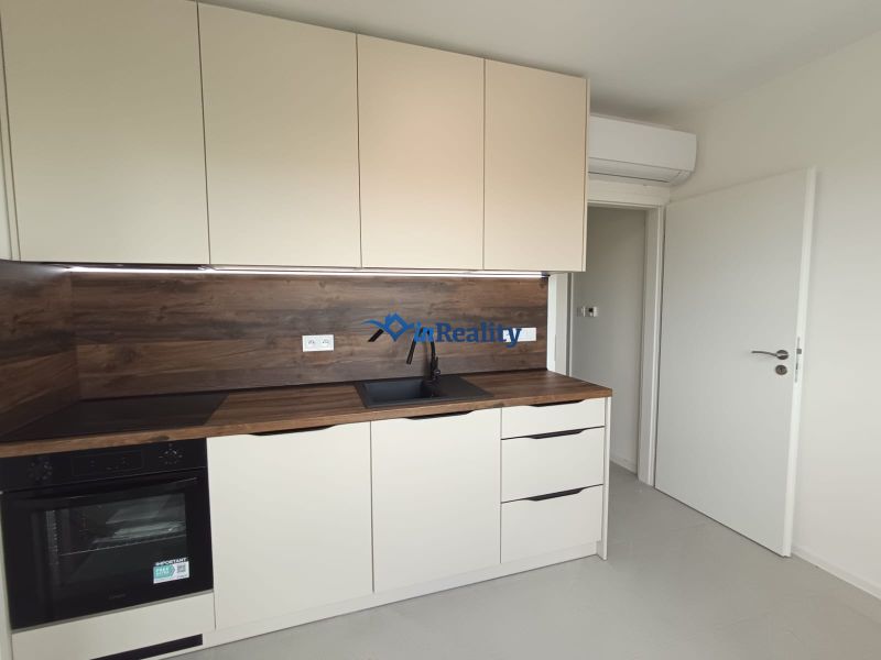 A kitchen in a 2-room apartment with white cabinets and a wood-patterned floor.