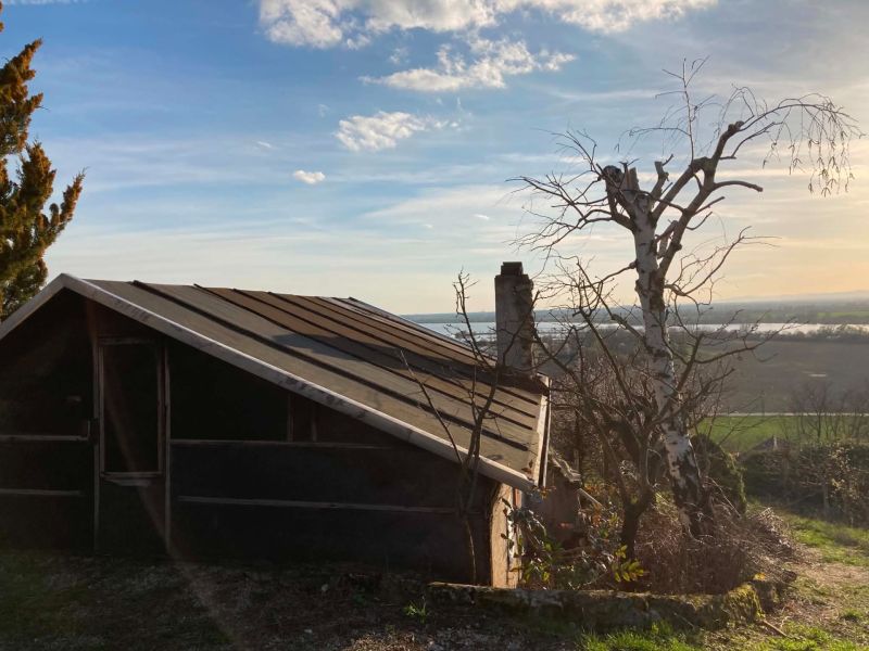 A cottage in the bank with a view of the countryside and trees around.