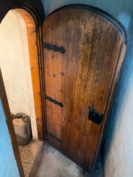 Old wooden door in the cabin with a visible canister in a narrow space.