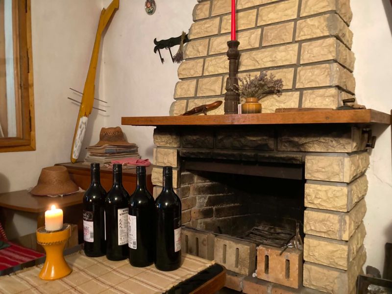 In the chalet, there is a brick fireplace, wine bottles, and a candle on the table.
