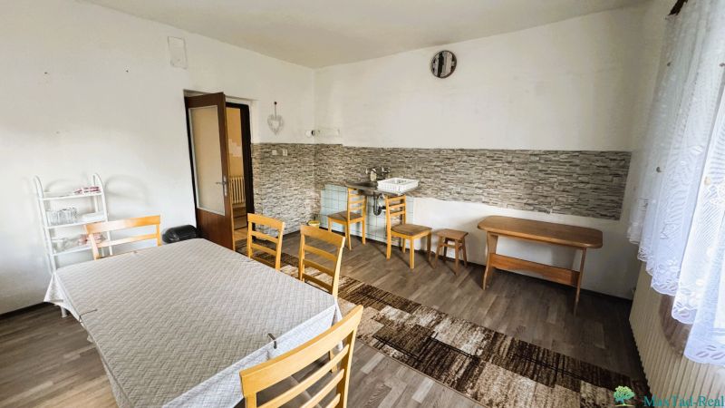 Dining room in a family house with wooden floor decor, simple furniture, and a sink.