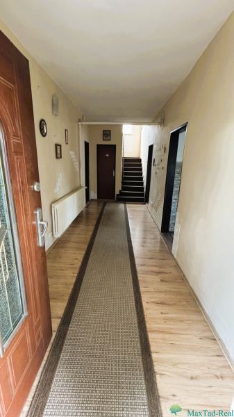 Entrance hallway in a family house with a wooden decor floor and a carpet runner.