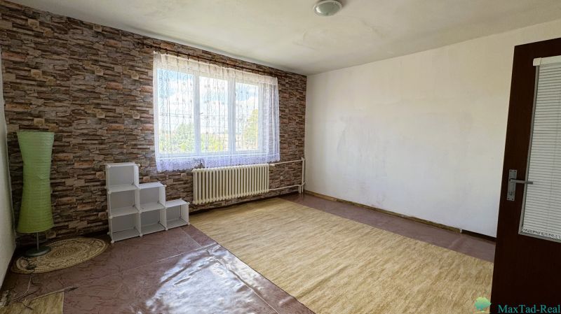 A room with a large window, carpet, and brick-patterned walls in a family house.