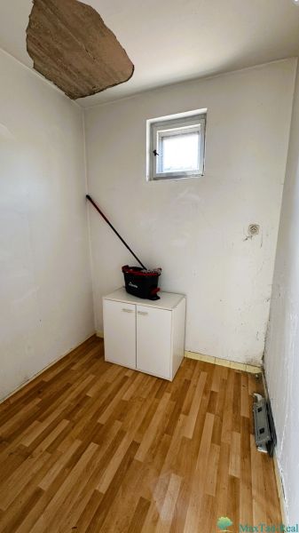 A small room with a window, a wardrobe, and a wooden decor floor in a family house.