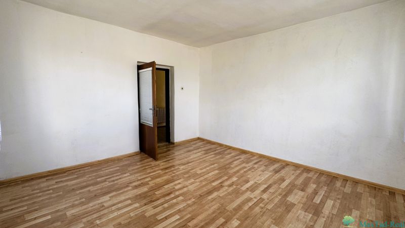 A room in a family house with a wooden decor floor and open doors.