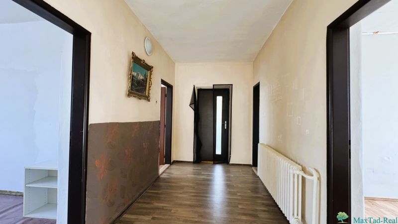 A hallway in a family house with a wooden decor floor and a painting on the wall.