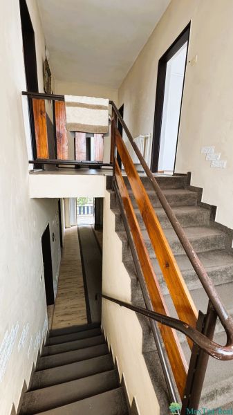 A staircase in a family house with a wooden railing and carpet on the steps.