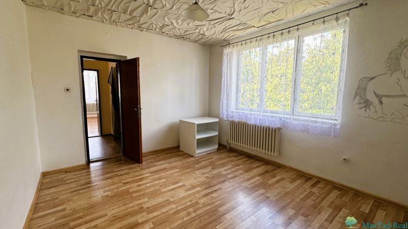 A room with a wooden decor floor, a cabinet, and a painting on the wall in a family house.