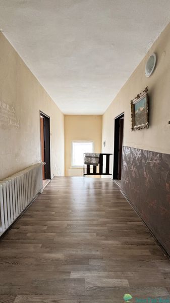 A hallway in a family house with a wooden decor floor, decorative walls, and a radiator.