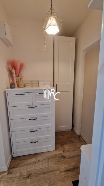 A room in a one-bedroom apartment with a chest of drawers, a wardrobe, and a floor with a wooden decor.