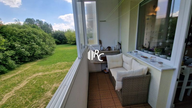 Glazed loggia with a view of greenery, cozy sofa and decorations, 1-room apartment.