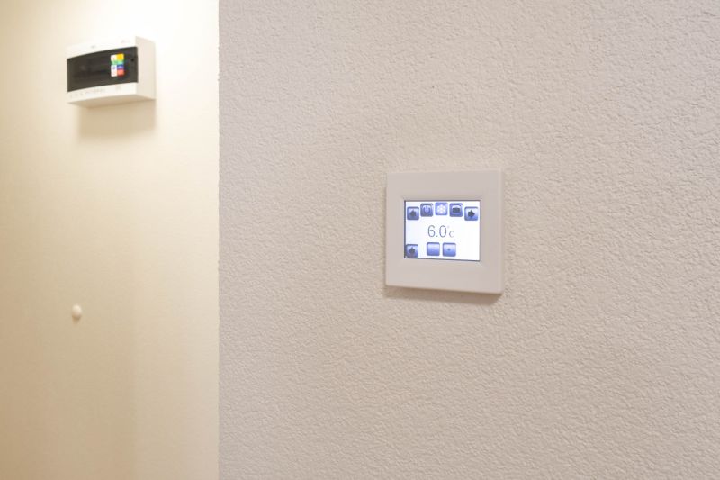 Adjustable thermostat on the wall in a studio apartment, simple design, white background.