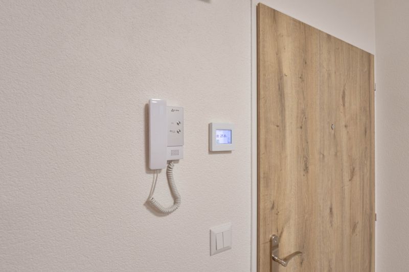 A door with a wooden decor and an intercom in a studio apartment.