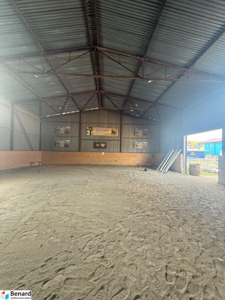 The interior of a building with a sand floor and a metal roof.