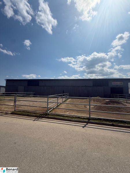 A building in Hniezdne with a fenced enclosure and a blue sky.