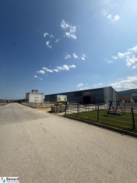 An industrial building in Hniezdne with a clear blue sky and an access road.