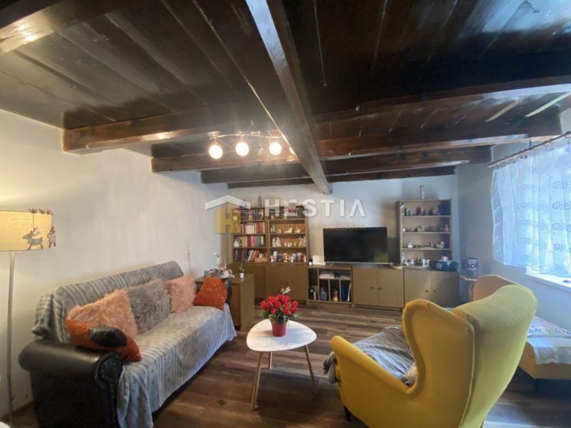 Living room in a family house with a wooden ceiling, comfortable seating, and decorative lighting.