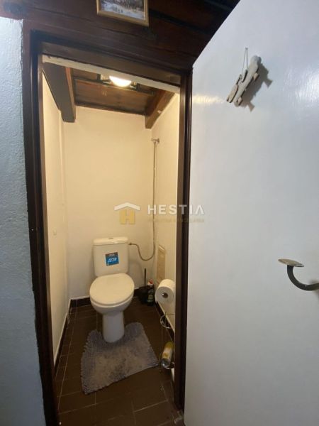 A toilet in a family house with dark tiles and white walls.