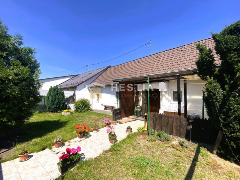 A family house in Borský Mikuláš with a garden, flowers, and a lawn in a sunny yard.