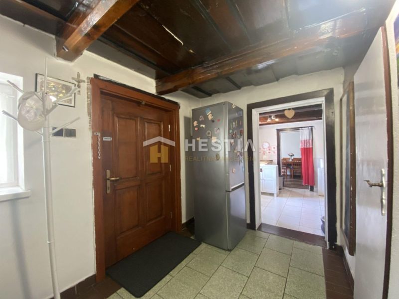 Interior of a family house with a wooden ceiling, hallway, and kitchen.
