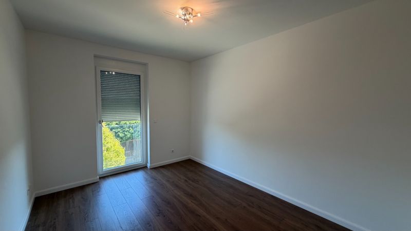 A room in a 3-room apartment with white walls and a wooden decor floor.
