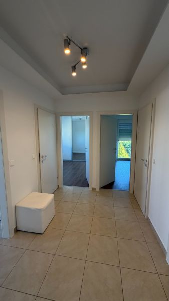 A hallway in a 3-room apartment with ceramic tiles and three white doors.