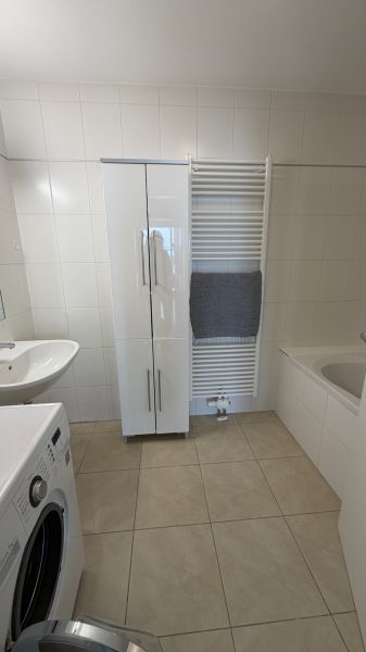 A bathroom in a 3-room apartment, with white furniture and a washing machine.